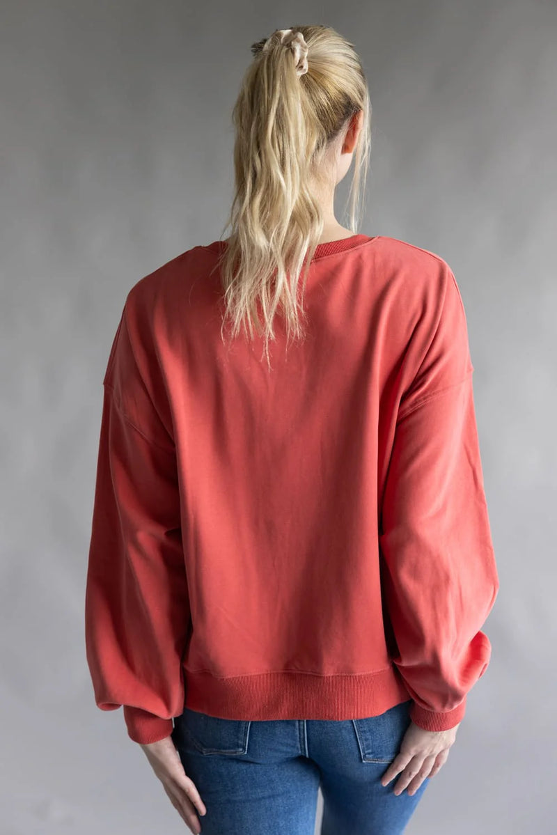 Model wearing dark coral Christmas sweater with nutcracker and tree corduroy patch framed by lace — festive holiday pullover available at TandyWear Boutique in Commack, NY. solid plain back view