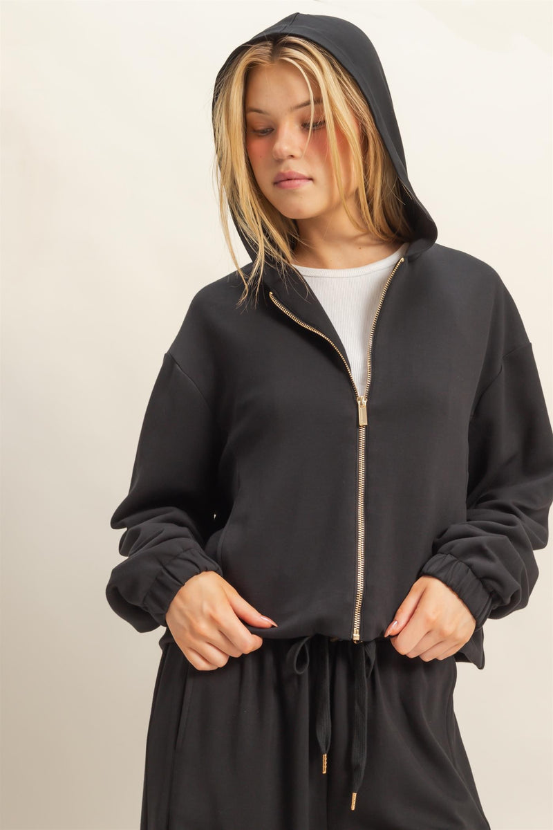 Soft black hoodie with a zip front, relaxed fit, and ribbed cuffs, perfect for stylish comfort in Long Island boutique fashion.