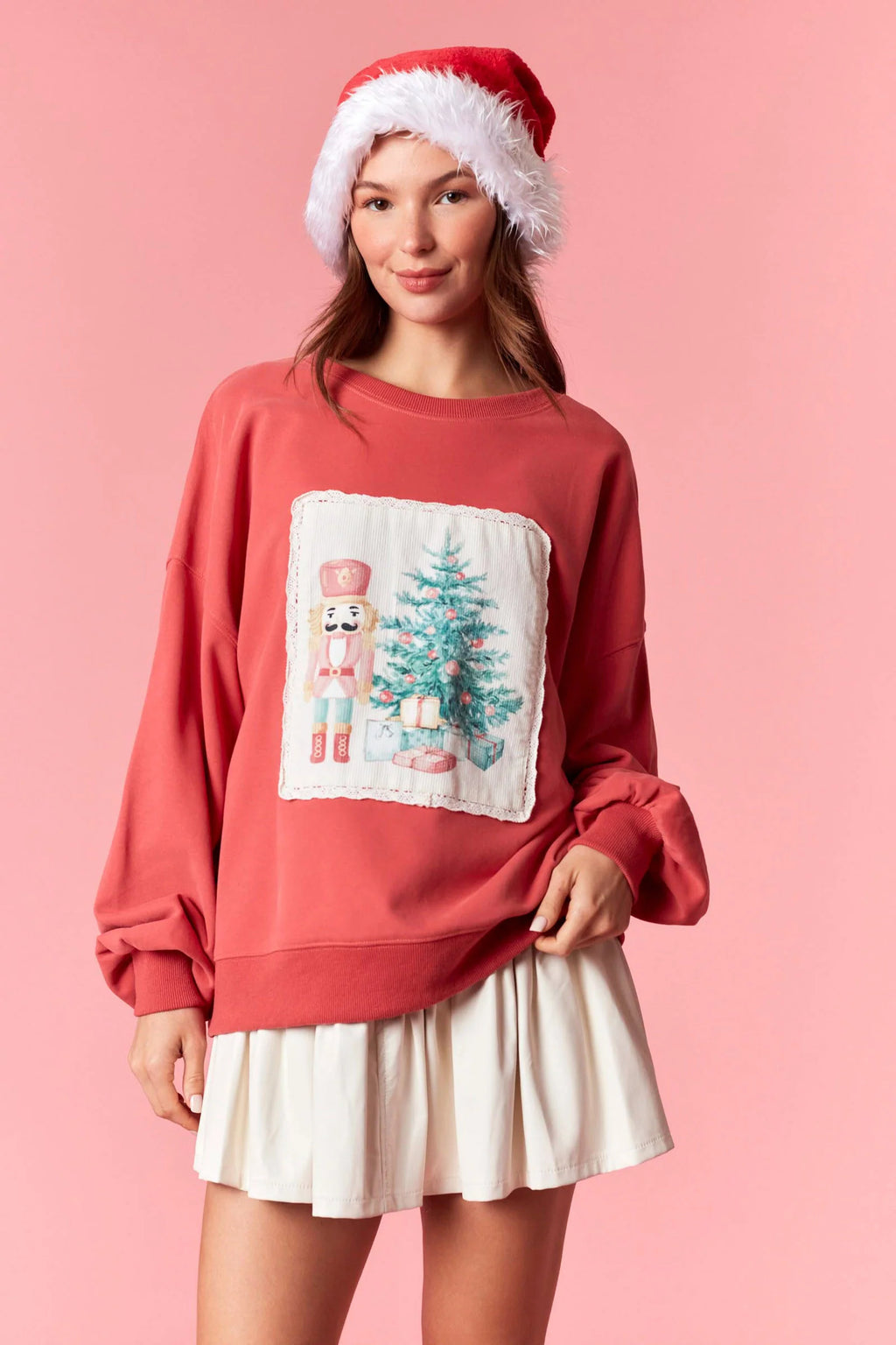Model wearing dark coral Christmas sweater with nutcracker and tree corduroy patch framed by lace — festive holiday pullover available at TandyWear Boutique in Commack, NY. front view