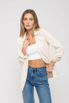 Light beige 3/4 ruched sleeve blazer paired with a white crop top and high-waisted blue jeans, perfect for Long Island boutique fashion.