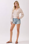 Soft brush ribbed surplice long sleeve top in light beige, featuring voluminous sleeves, paired with denim shorts for a chic Long Island boutique fashion look.