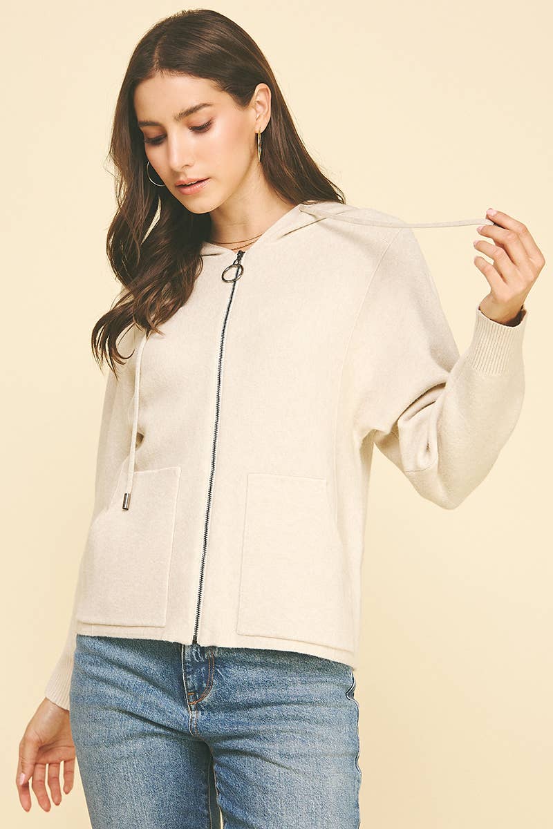 Woman wearing a beige jacket with a zipper on a beige background