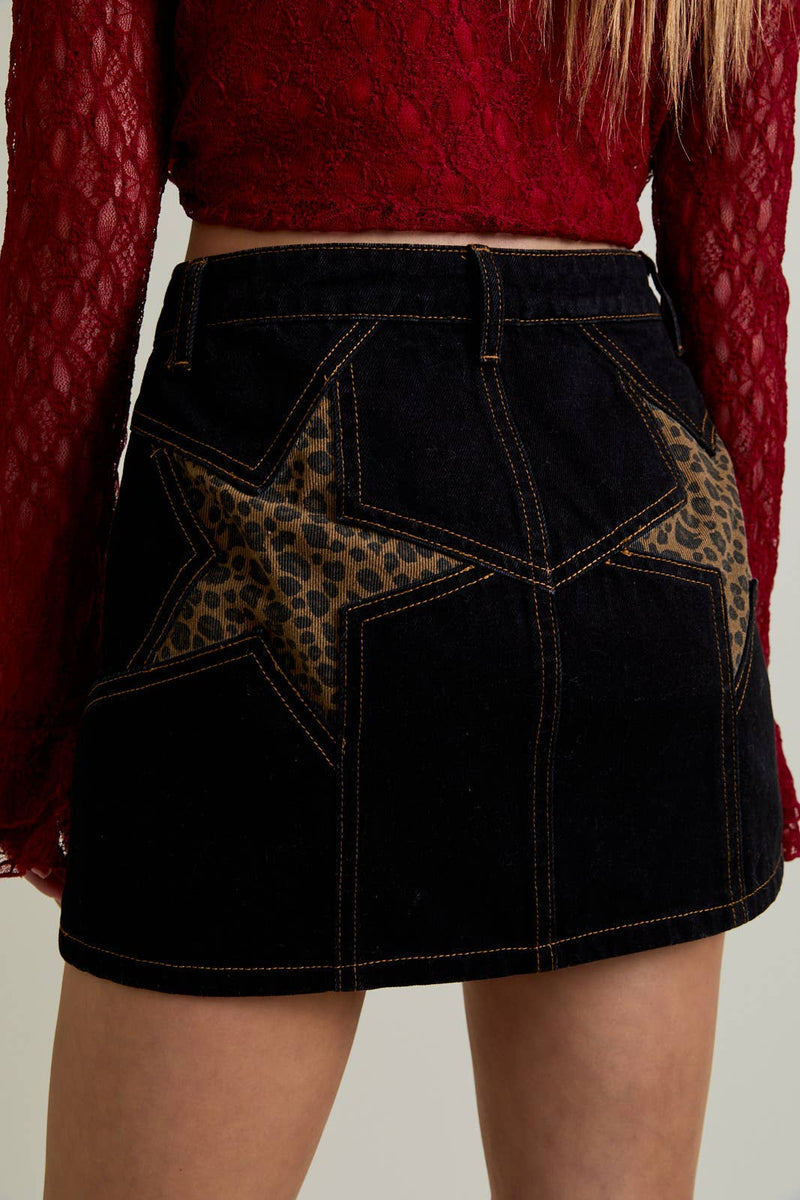 Black denim skirt featuring bold leopard print star patches and contrast stitching, perfect for trendy Long Island boutique fashion.