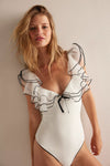 White bodysuit with delicate black ruffled sleeves and a front tie, showcasing a chic style perfect for Long Island boutique fashion.