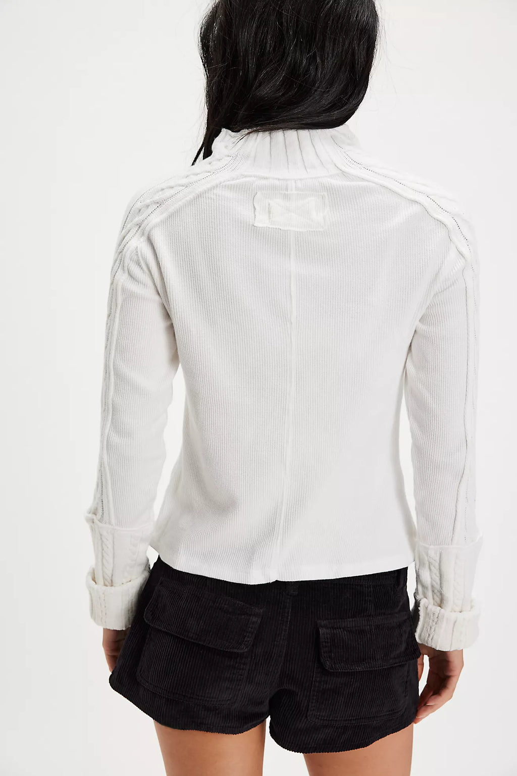 Lightweight white ribbed top with a ruffled neckline, styled with a chic black leather jacket and matching corduroy shorts for trendy Long Island boutique fashion.