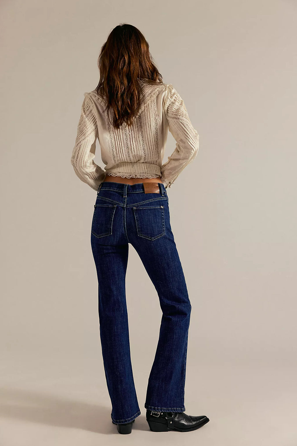 High-rise bootcut jeans in dark denim featuring a double knot detail, paired with a cozy long cardigan for a trendy Long Island boutique fashion look.