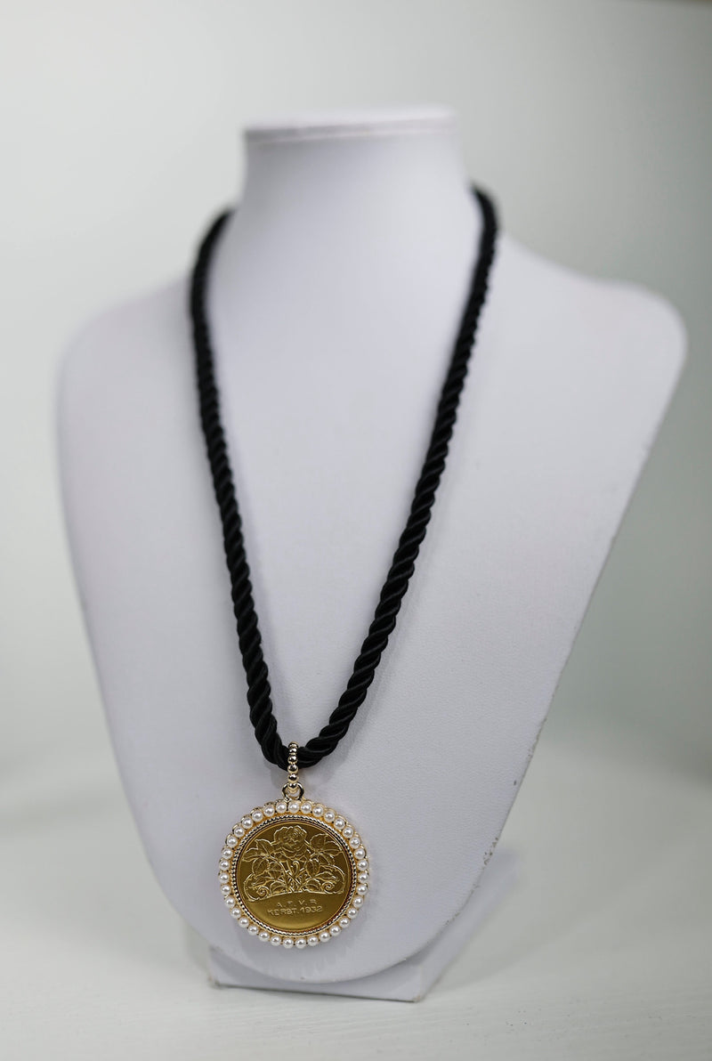 Elegant black twisted rope necklace featuring a golden medallion charm surrounded by delicate pearls, showcasing Long Island boutique fashion.