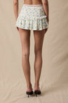 High-waisted mini skort featuring a delicate ditsy floral pattern, ruffle detailing, and a front tie, perfect for Long Island boutique fashion.
