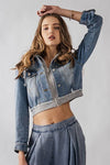 Cropped denim jacket featuring a distressed zip front and jersey hood, perfect for a trendy Long Island boutique fashion look.