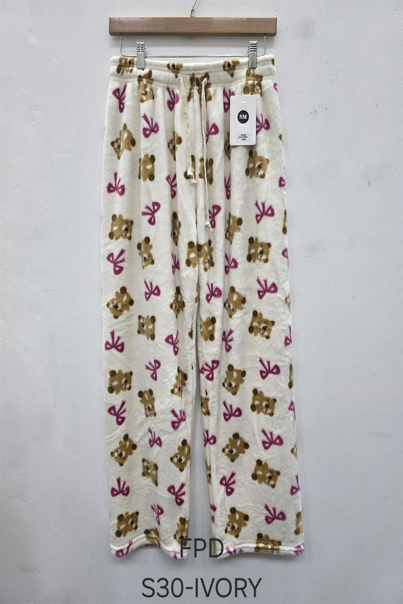 Ivory pants with teddy bear and scissors pattern on a hanger against a white background