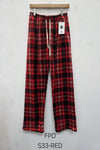 Red and black plaid pants on a hanger against a white background