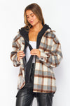 Woman wearing a plaid jacket with a black hood on a white background