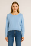 Woman wearing a light blue sweater and blue jeans on a beige background