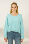 Woman wearing a light blue sweater and jeans on a white background
