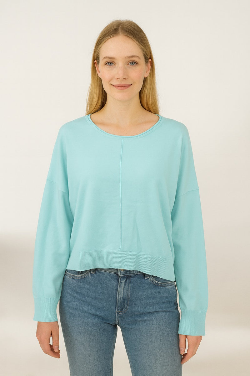 Woman wearing a light blue sweater and jeans on a white background