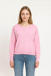 Woman wearing a pink sweater and blue jeans on a white background