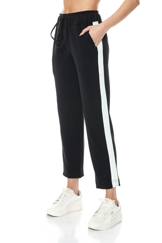 Black straight leg pants with white side stripes and a drawstring waist, perfect for casual Long Island boutique fashion.