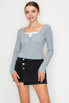 Light blue half button long sleeve crop top with a fitted design, perfect for layering in Long Island boutique fashion.