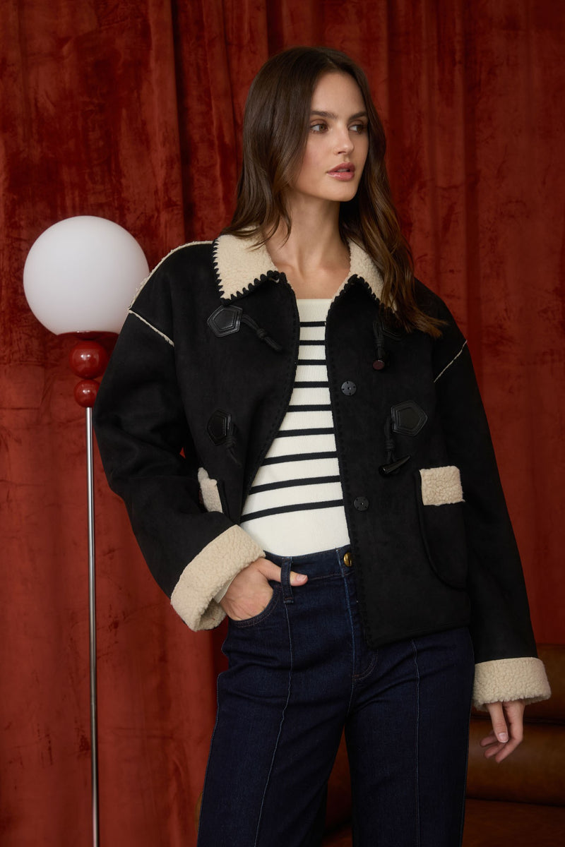 A stylish black faux shearling suede toggle button jacket with a cozy cream collar, perfect for Long Island boutique fashion enthusiasts.