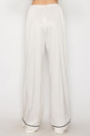 Flowy wide leg pajama pants in soft cream with contrasting black piping, perfect for lounging in stylish comfort from this Long Island boutique fashion.
