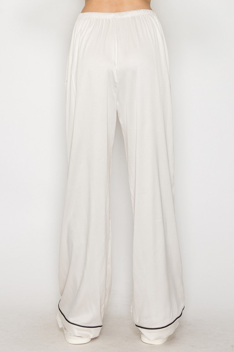 Flowy wide leg pajama pants in soft cream with contrasting black piping, perfect for lounging in stylish comfort from this Long Island boutique fashion.