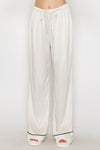 Soft, cream-colored contrast wide leg pajama pants with a drawstring waist and black detailing, perfect for Long Island boutique fashion.