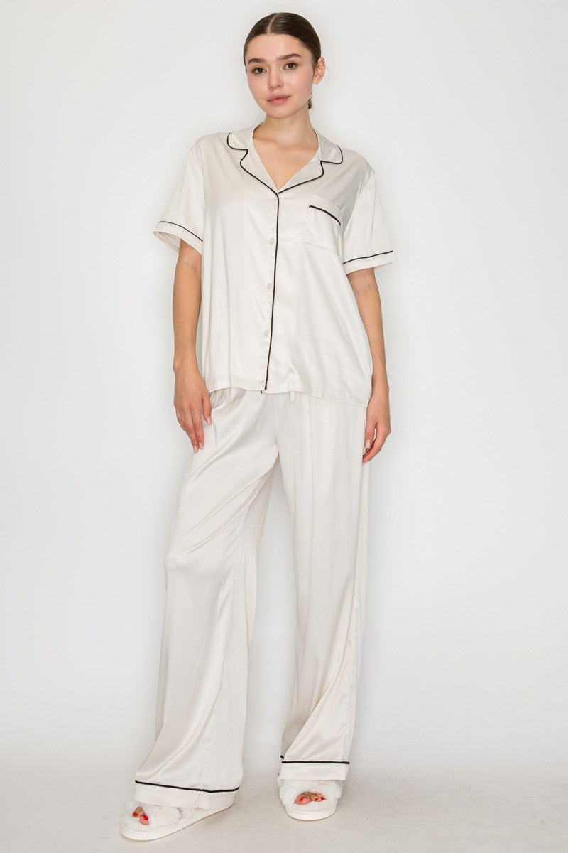Relaxed cream pajama top with contrasting black piping and a pocket, perfect for chic evenings in Long Island boutique fashion.
