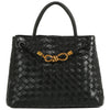 A sleek black woven satchel with a stylish brass knot detail, perfect for a chic outing in Long Island boutique fashion.