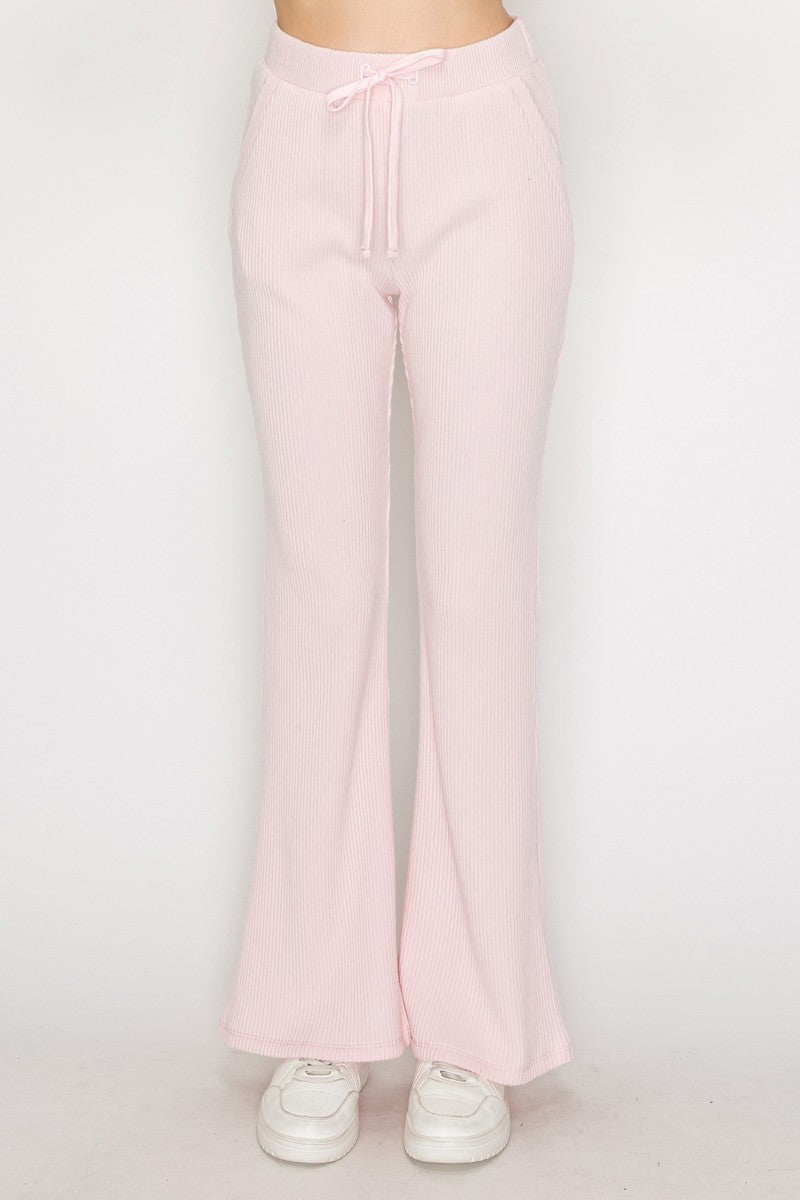 Light pink elastic wide leg pants with a ribbed texture and adjustable drawstring waistband, perfect for relaxed Long Island boutique fashion.