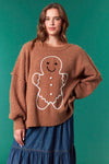 Model wearing Gingerbread Man Oversized Sweater in brown — soft fuzzy knit with large gingerbread graphic, available at TandyWear Boutique in Commack, NY. front view