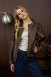 Brown collared zip-up washed faux leather jacket with a relaxed fit and side pockets, a stylish choice from a Long Island women's boutique.