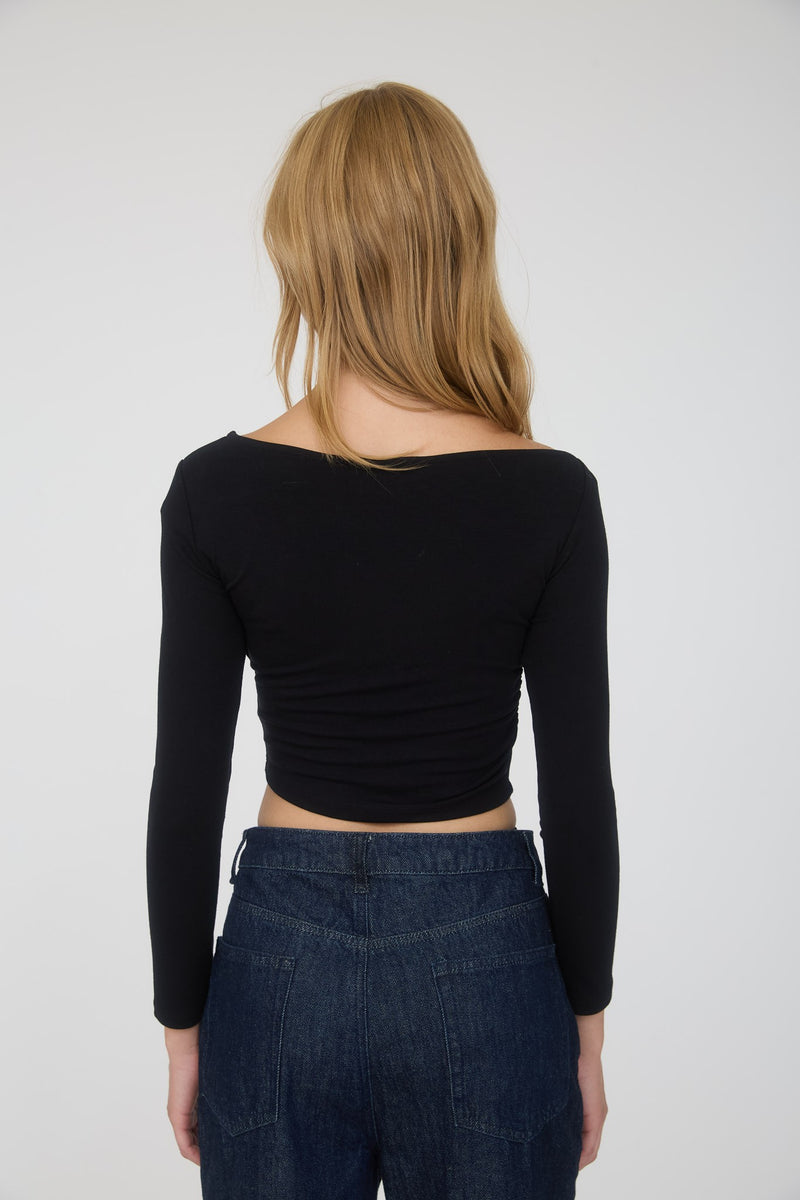 Asymmetrical black crop top featuring snap buttons and long sleeves, perfect for trendy Long Island boutique fashion.