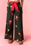 Model wearing Holiday Toy Soldier Cotton Poplin Pajama Pants in hunter green with red bow tie — festive nutcracker print sleepwear available at TandyWear Boutique in Commack, NY. front view