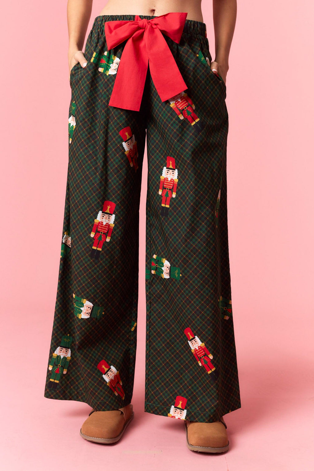 Model wearing Holiday Toy Soldier Cotton Poplin Pajama Pants in hunter green with red bow tie — festive nutcracker print sleepwear available at TandyWear Boutique in Commack, NY. front view