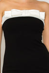 Strapless black capri dress featuring a bold white bow detail at the neckline, perfect for stylish outings in Long Island boutique fashion.