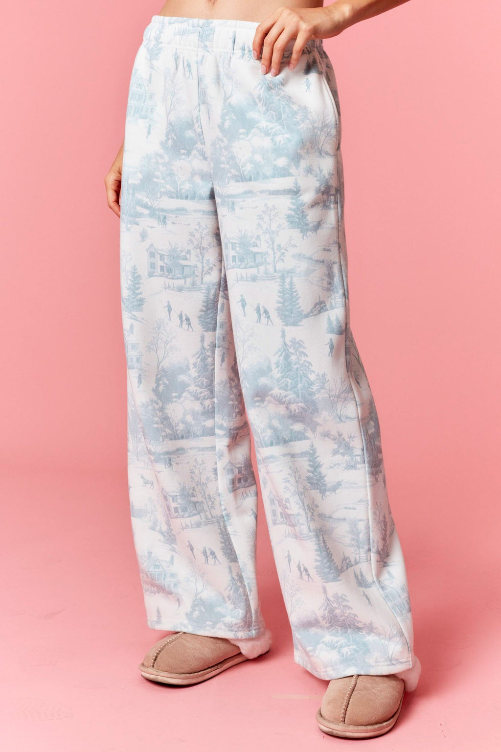 Model wearing Holiday Scenery Print Fleece Terry Sweatpants in dusty blue — relaxed-fit lounge pants with winter village print, available at TandyWear Boutique in Commack, NY. front view