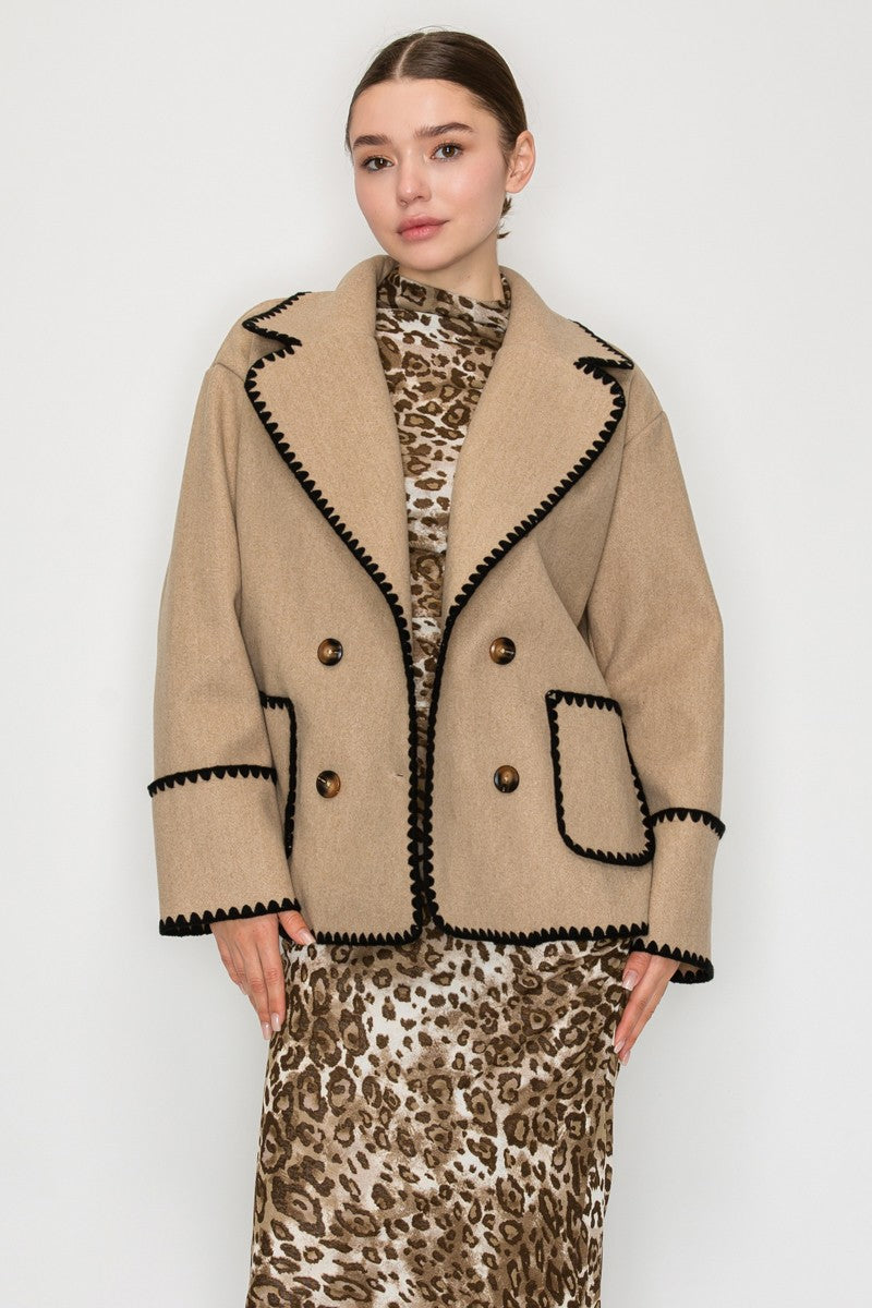 Double-breasted beige jacket with black blanket stitching and oversized lapels, perfect for chic Long Island boutique fashion.