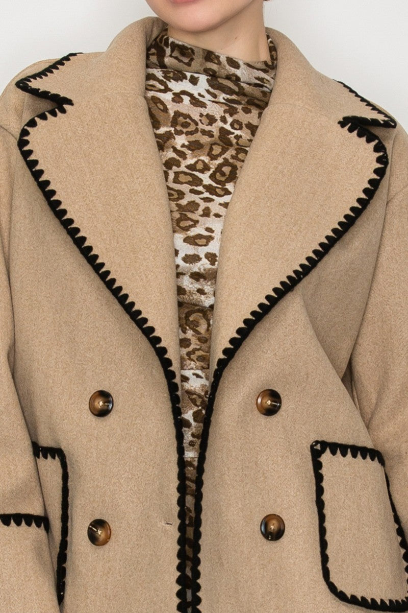 Double breasted beige jacket with black blanket stitch detailing and large buttons, perfect for stylish layering in Long Island boutique fashion.