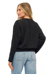 Woman wearing a black sweater and light blue jeans on a white background