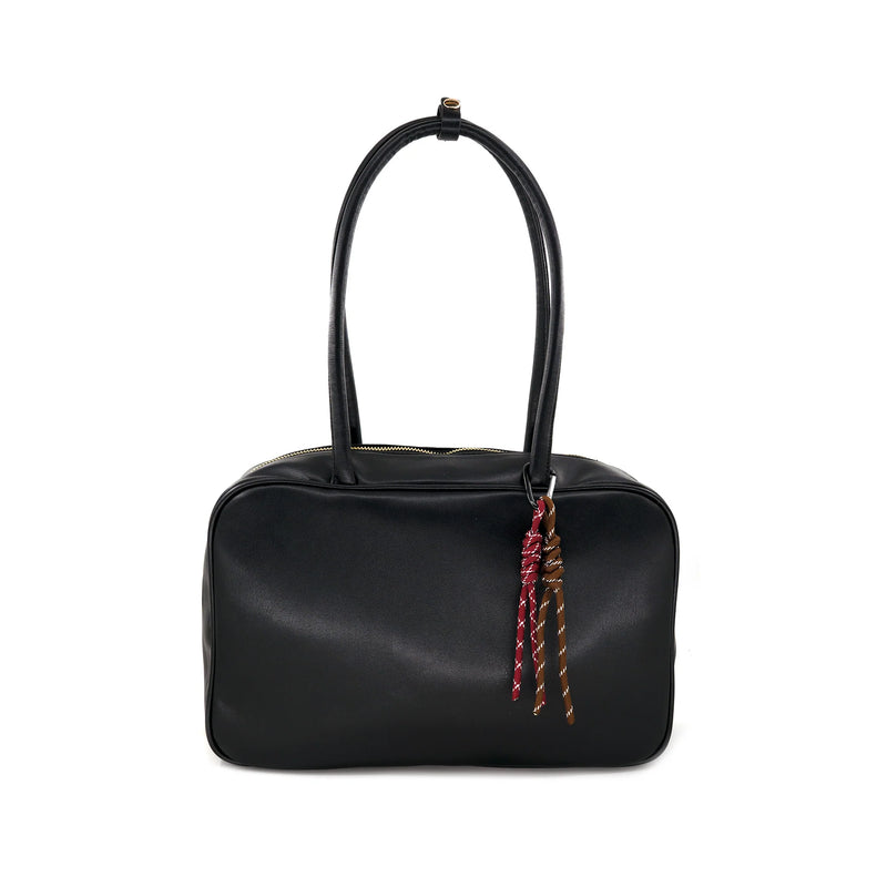 Boxy black handbag with smooth matte finish, double handles, and playful tassel detail, perfect for Long Island boutique fashion.