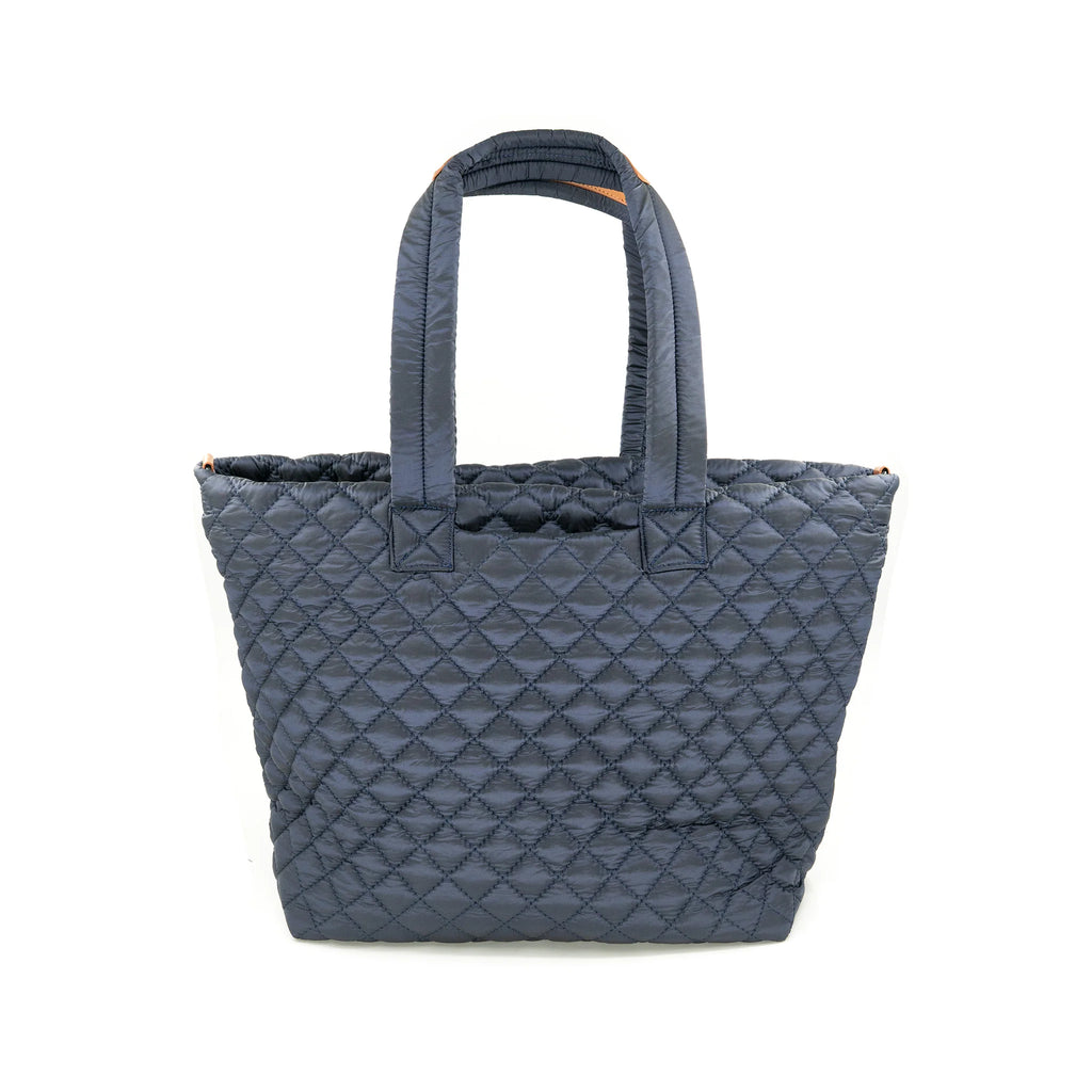 Quilted in elegant silver nylon, this spacious tote bag with sturdy handles showcases a chic and functional design for Long Island boutique fashion.