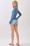 Fitted long sleeve V-neck top in a soft blue hue, perfect for layering, showcased with distressed denim shorts in Long Island boutique fashion.