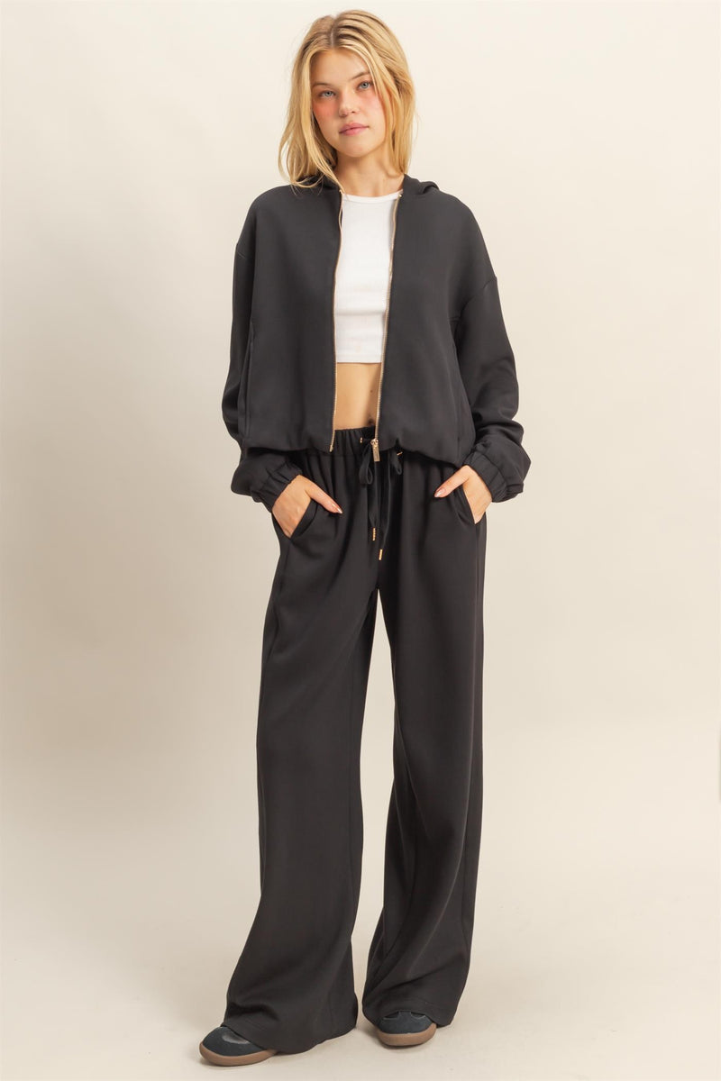 Chic black zip-front hoodie with a cropped fit, elastic cuffs, and a relaxed silhouette, perfect for Long Island boutique fashion.