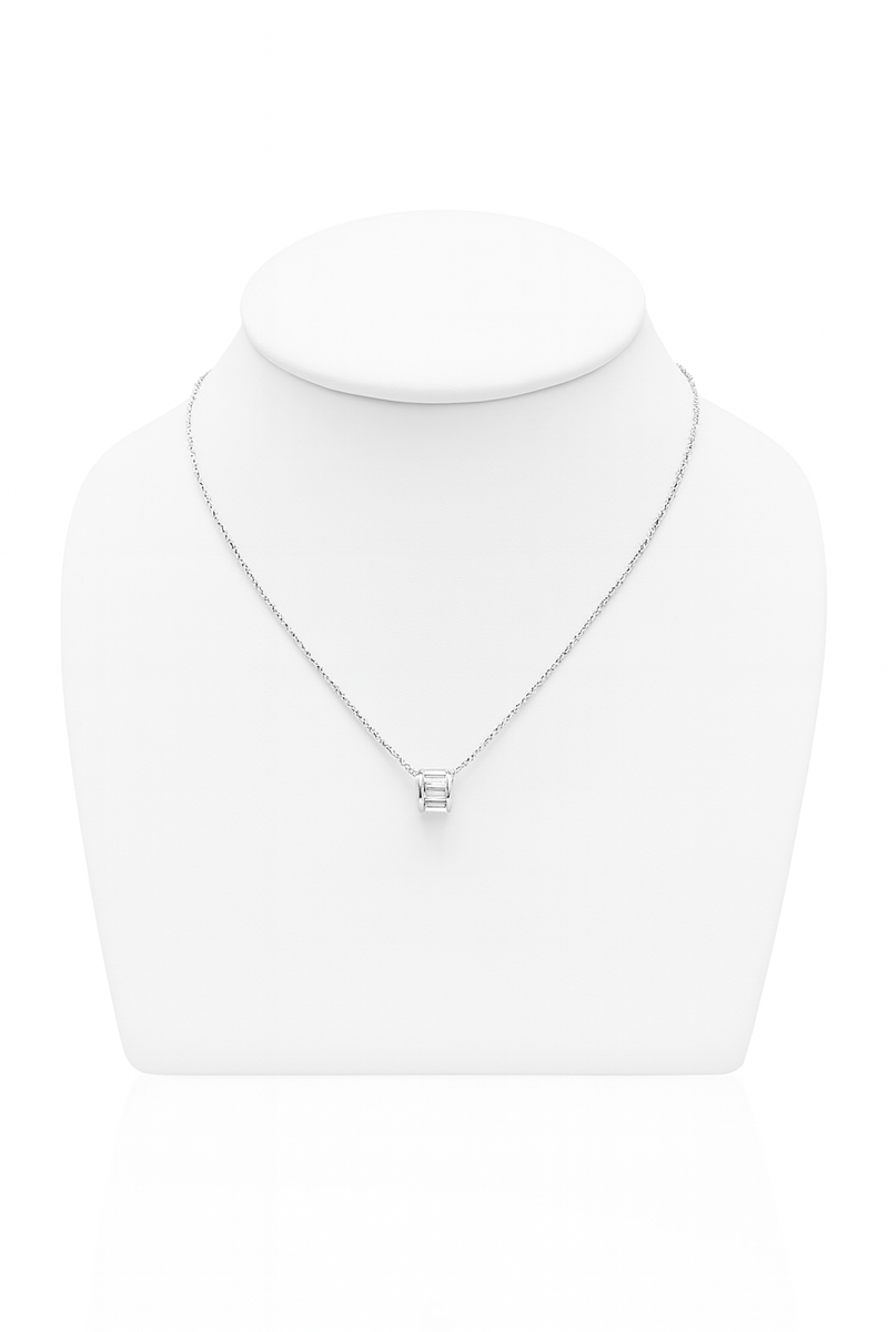 Model wearing a radiant silver-tone barrel pendant necklace with clear baguette-style stones on a delicate chain, resting at the collarbone.