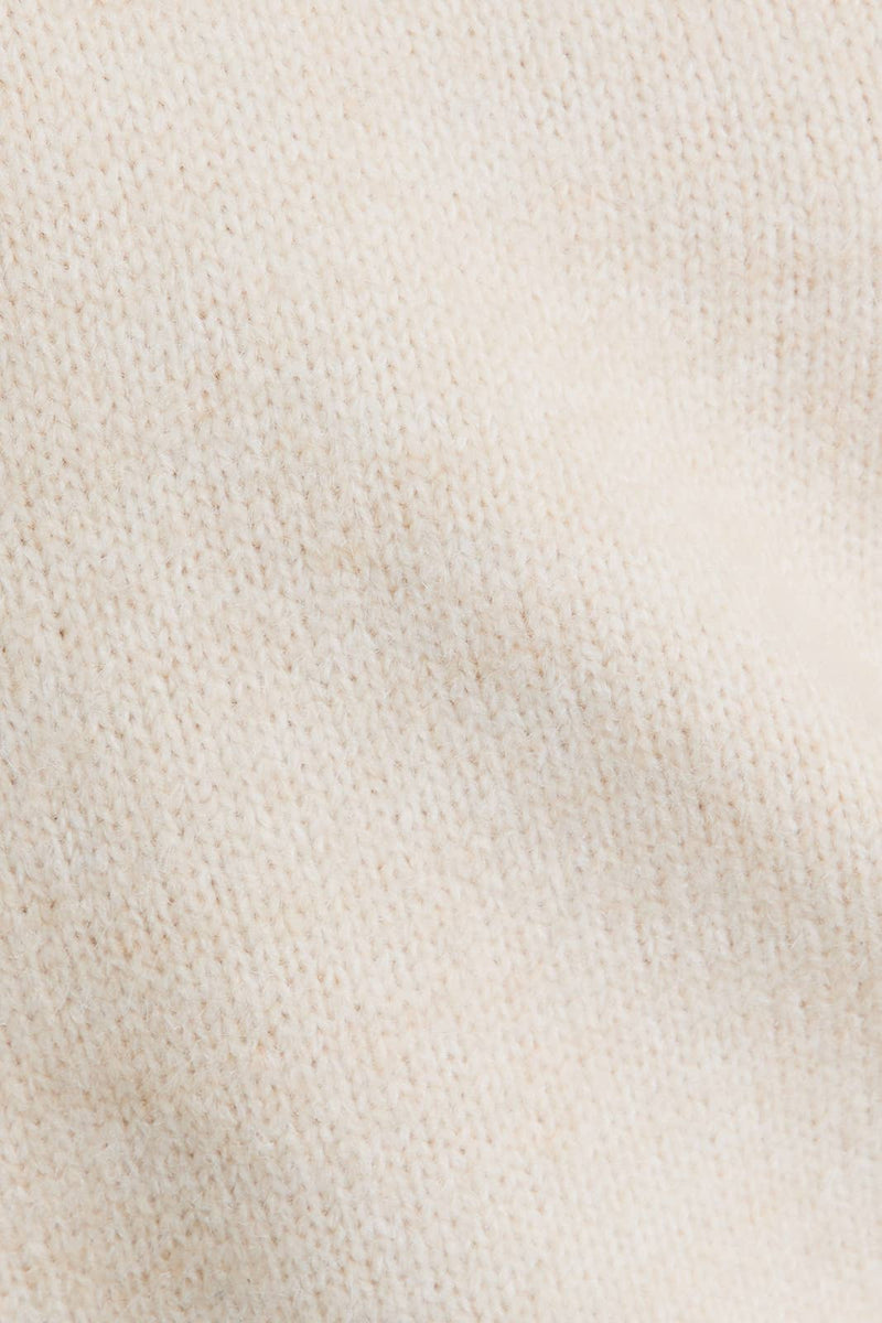 Cream-colored asymmetrical shoulder sweater top with a soft texture, perfect for Long Island boutique fashion enthusiasts.