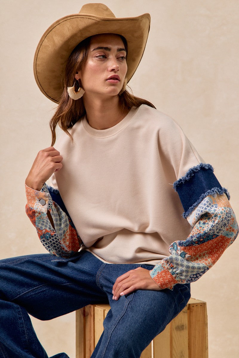 Beige French terry top with printed denim sleeves, featuring a frayed edge, perfect for casual style from a Long Island fashion boutique.