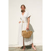 Elegant white maxi dress with short sleeves, button details, and a wicker belt, paired with a woven handbag for a fresh Long Island boutique fashion look.