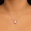 Model wearing a radiant silver-tone barrel pendant necklace with clear baguette-style stones on a delicate chain, resting at the collarbone.