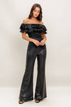 Off-the-shoulder black coated woven jumpsuit with ruffled detailing and wide-leg fit, ideal for Long Island boutique fashion.