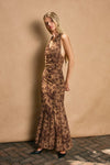 Draped halter neck maxi dress in warm brown with floral patterns, perfect for elegant evenings at a Long Island fashion boutique.
